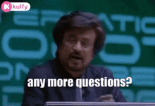 a man is sitting in front of a green board and says any more questions ?