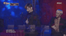 two men on a stage with a mbc logo in the corner