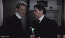 two men in suits and ties are standing next to each other and looking at each other .