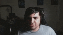 a man is sitting in a chair in a dark room with posters on the wall behind him .