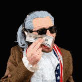 a man wearing a wig and sunglasses is holding a 100 dollar bill in front of his face