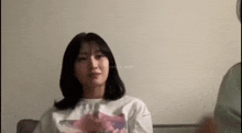 a woman is sitting on a couch looking at the camera while a man stands behind her .