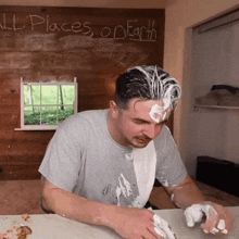 a man with whipped cream on his face is sitting in front of a wall that says " all places on earth "