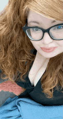 a woman wearing glasses and a nose ring is smiling