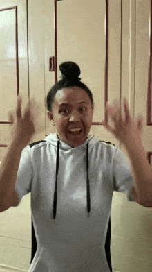 a woman wearing a white hoodie is making a funny face
