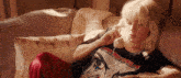 a woman is laying on a couch talking on a phone with her eyes closed