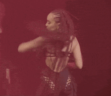 a woman with dreadlocks is dancing in a red light