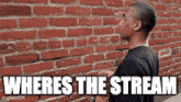 a man is standing in front of a brick wall and says where 's the stream