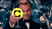 a man in a tuxedo is holding a wine glass with a yellow circle with the letter c on it