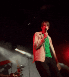 a man in a green shirt is singing into a microphone on a stage