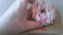 a person is holding a pink and white donut with sprinkles in their hand