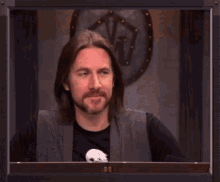 a man wearing a black shirt with a skull on it laughs