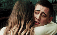 a man and a woman are hugging each other and the woman is crying .