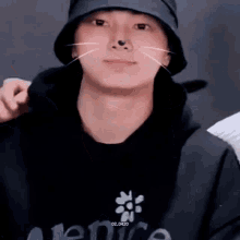 a close up of a person wearing a hat and a hoodie with a cat nose .