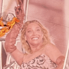 a woman in a pink dress is smiling and holding up her arm