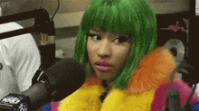 a woman with green hair is sitting in front of a microphone wearing a colorful coat .