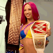 a woman with pink hair is holding a wwe title belt