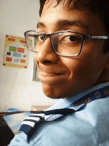a man wearing glasses and a blue shirt with a blue lanyard that says chaka