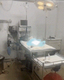 an operating room with a monitor on the wall above a bed