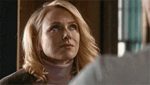 a woman in a pink turtleneck is looking at a man in a suit .