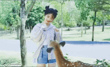a girl standing next to a deer with the letter l on the bottom left