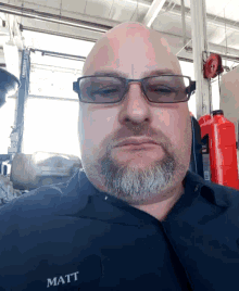 a bald man with glasses and a beard has the name matt on his shirt pocket