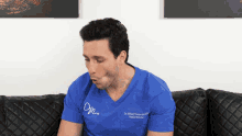 a man wearing a blue shirt that says dr. wilfred t. torkanski on it is sitting on a couch