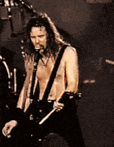 a man with long hair singing into a microphone