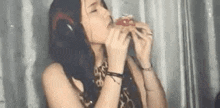 a woman wearing headphones is eating a hamburger while sitting in front of a microphone .