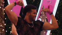 a man in a black shirt is flexing his muscles in front of a pink sign