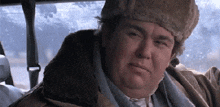 a man wearing a fur hat and a jacket is sitting in a car .