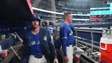 a baseball player wearing a blue jays jersey walks in the dugout