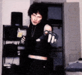 a man in a black vest and gloves is pointing his finger at the camera