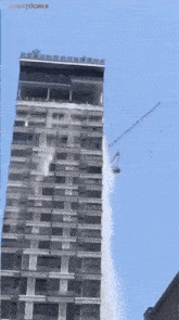 a tall building with a crane attached to it and the word studios on the bottom right