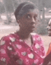a woman in a pink shirt with hearts on it is talking to another woman