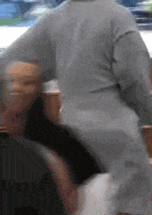 a person in a grey sweater is standing next to another person in a black shirt .