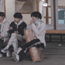 a man sitting on a stump with a bag of popcorn on his lap