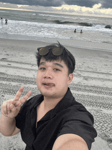 a man giving a peace sign on the beach