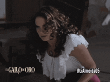 a woman in a white top with the words el gallo de oro written on it