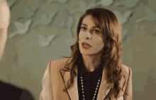 a woman in a suit and pearls is talking to a man .
