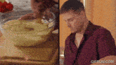 a man is mixing something in a bowl and another man is looking at something in a bowl