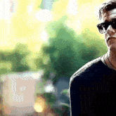 a man wearing sunglasses is standing in front of a blurry background