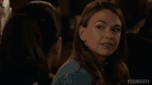 a woman is making a funny face while sitting at a table with another woman .