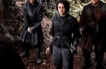 a group of people standing next to each other in the woods .