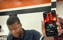 a man is holding up a cell phone with a picture of a man on it