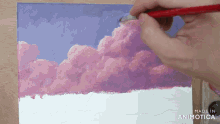 a person is painting pink clouds on a canvas