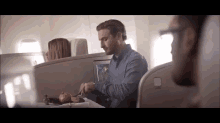 a man sits at a table on an airplane with a tray of food on it
