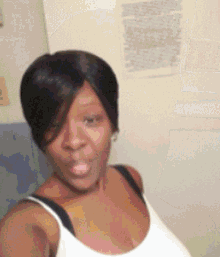 a woman is taking a selfie in a white tank top