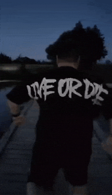 a man wearing a black shirt that says live or die on the back