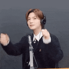 a young man wearing headphones is standing in front of a microphone and making a funny face .